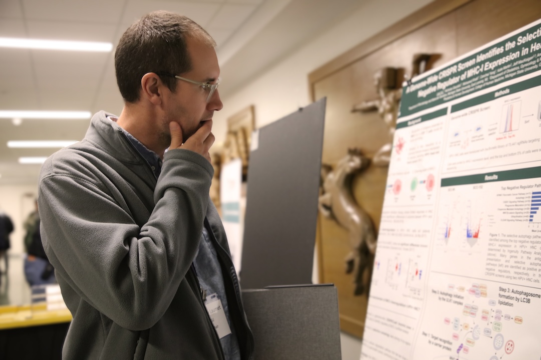 Co-Chair Geoffroy Laumet looks at a research poster during the Immunology Research Symposium at MSU.