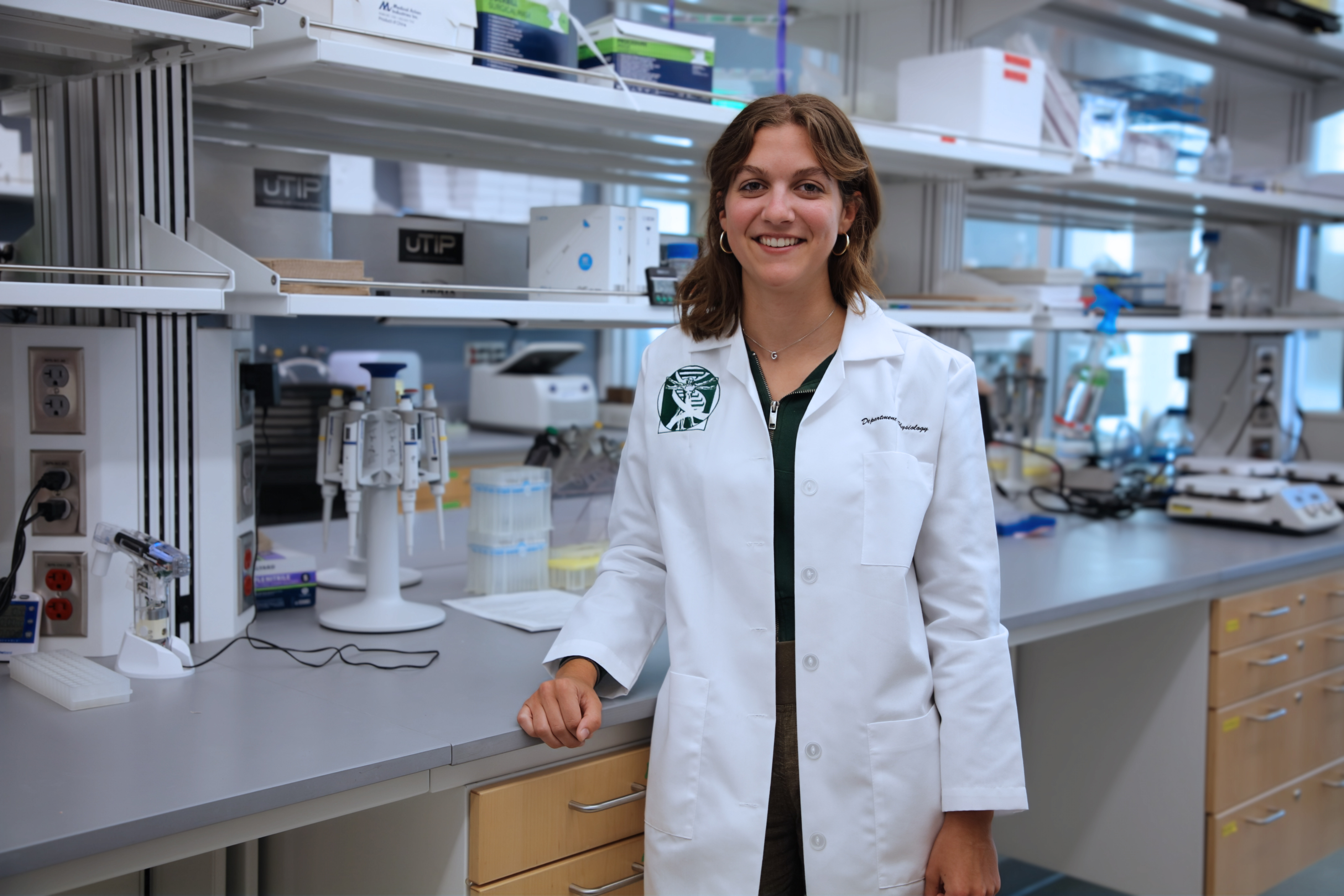 Gwen Urbain poses in a laboratory wearing a white lab coat.