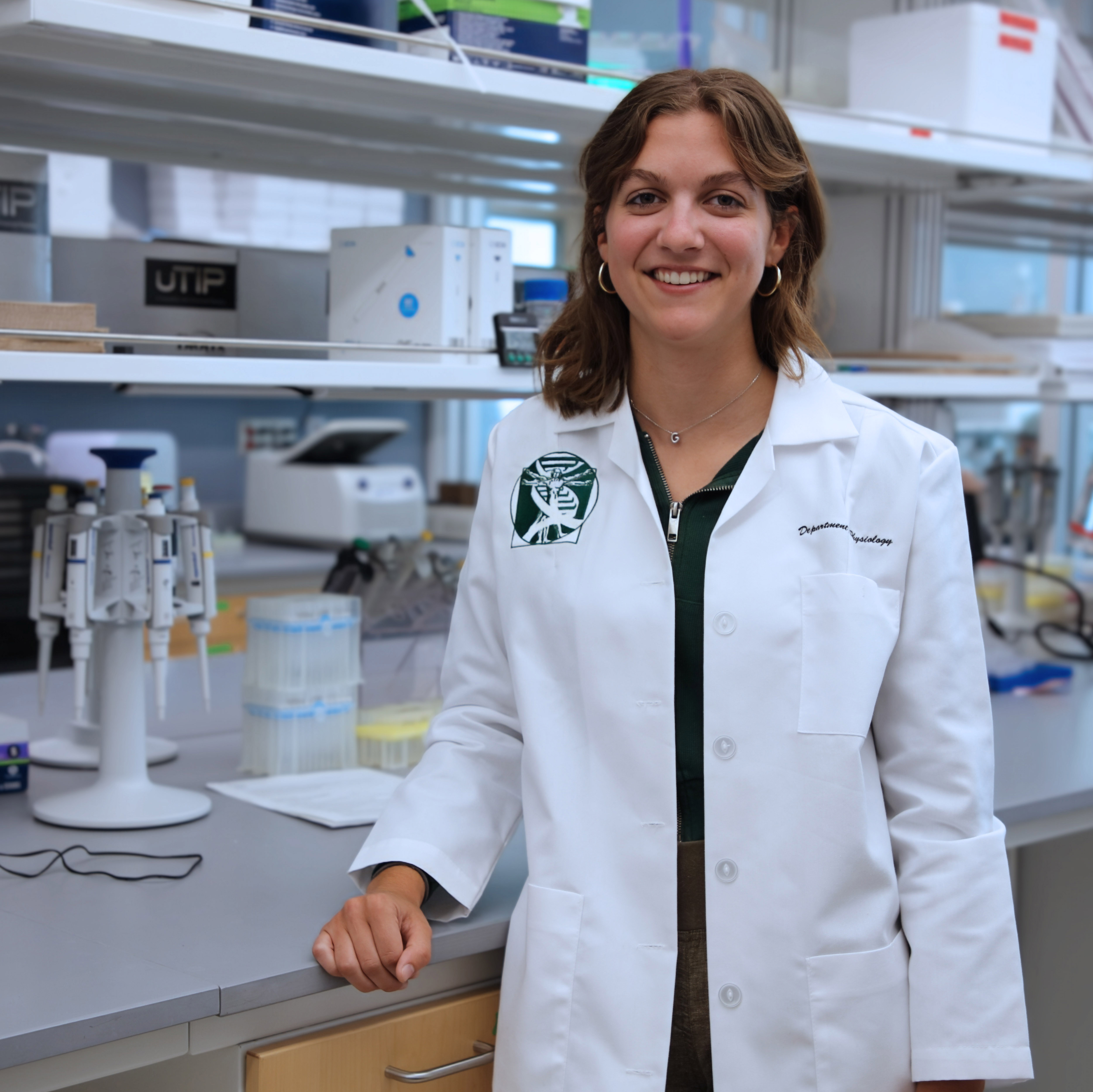 Gwen Urbain poses in a laboratory wearing a white lab coat.