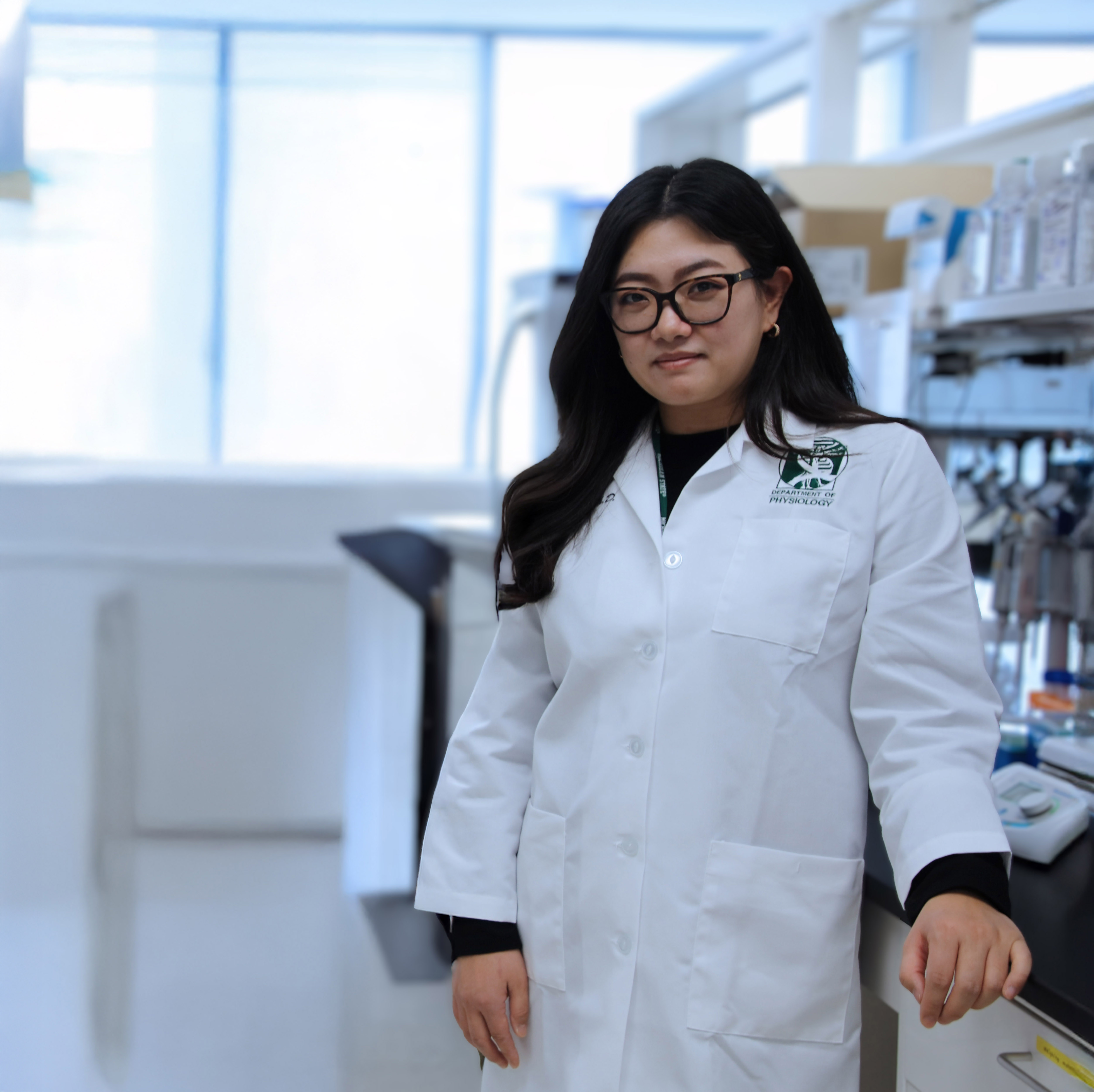 Eunhee Yi in a white lab coat poses in a lab.